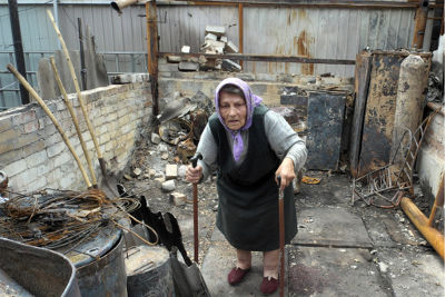 Жительница района Артема города Славянска (Украина) стоит среди обломков того, что раньше было ее летней кухней, июль 2014 года.Фото: УВКБ / Ива Зимова