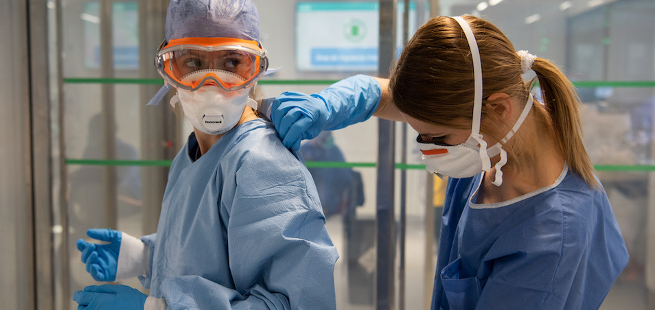 two women healthcare workers in Barcelona put on protective gear. Photo: Hospital Clínic/Francisco Àvia
