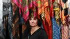 A Kazakh woman pictured in a vivid marketplace in front of colorful textiles. Photo: UN Women/Janarbek Amankulov