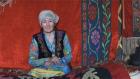 A Kazakh woman pictured sitting on colorful traditional rugs. Photo: UN Women/Janarbek Amankulov